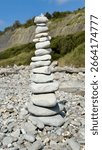 A Stack Of Beach Pebbles On A Pebbly Beach With A Rock Face In Background 