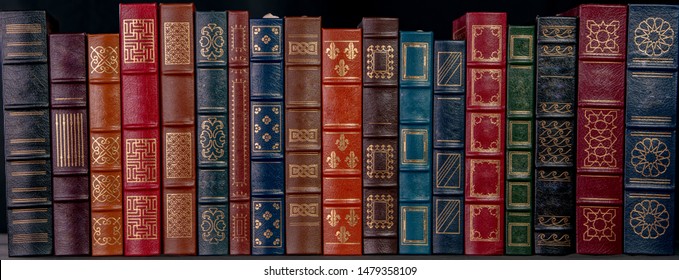 A stack of beautiful leather bound books with golden decoration against a black background. - Powered by Shutterstock