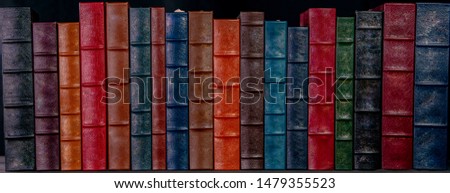 A stack of beautiful leather bound books with a black background.