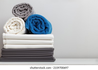 Stack of bed linen, sheets, rolled up terry towels on the table