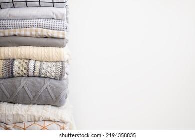 Stack bed linens and knitted warm plaids domestic soft textile with copy space isolated on white background. Heap of Scandinavian hygge fabric duvet cover cotton sheet and pillowcase storage organize