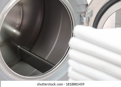 Stack Of Bed Sheets In Front  Of Industrial Laundry Washing Machine. Metal Tub Is Inside. Focused On Washing Machines. Shot Taken In The Factory.