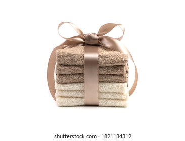 A stack of beige and white towels tied with a satin ribbon on a white background. Gift set, side view horizontal orientation. The concept of home textiles.