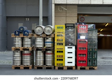 Stack Of A Beverage Delivery In Berlin With Beverage Crates And Metal Barrels At The Back Of A Restaurant.	