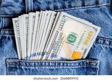 a stack of bills of one hundred and 100 dollars lies in the back pocket of blue jeans and peeks out of the pocket, a lot of money in the pocket