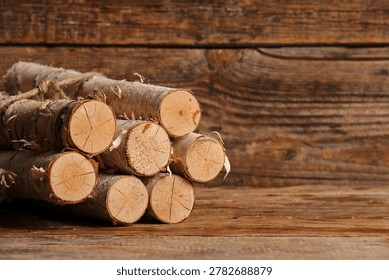 Stack of birch logs tied with rope on wooden background