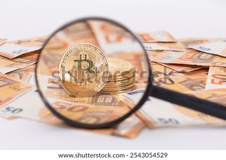 A Stack of Bitcoin Coins Visible Through a Magnifying Glass on the 50-Euro Banknotes. Euro Currency and Crypto Currency. Orange Paper Money. A Lot of Fifty-Euro Bills. Anonymous Payments Concept