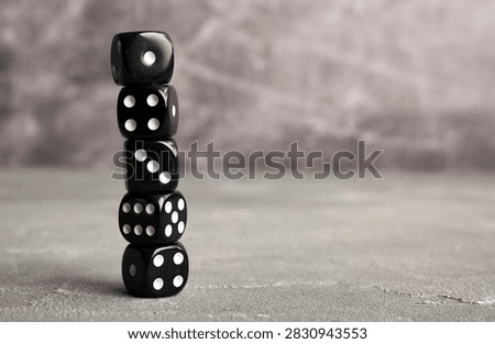 Stack of black dices on grey background