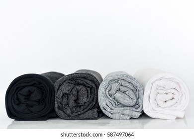 stack of black, grey and white (monochrome) t-shirt rolled up on white background, copy space