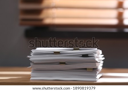 Stack of blank paper with binder clips on wooden table indoors. Space for text