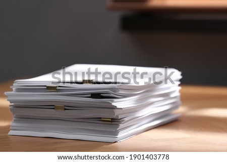 Stack of blank paper with binder clips on wooden table indoors