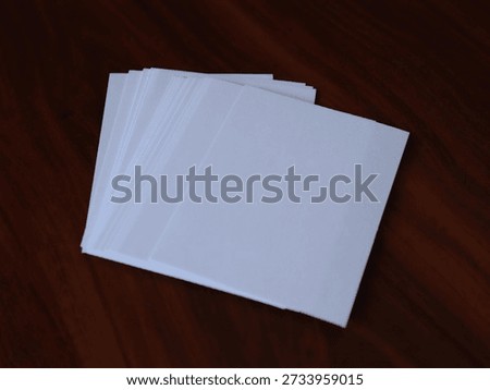 Stack of blank white paper sheets placed on a wooden table surface, showing clean edges and simple top view composition.