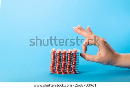 Stack of blisters with red pills on blue background and tin ok. Concept of pills for increasing immunity, immunosuppressants. Copy space for text