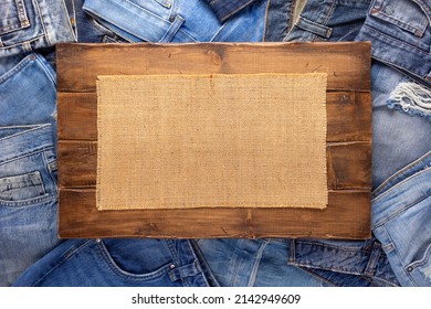 Stack Of Blue Jeans Denim And Wood Name Plate. Jeans Heap With Wooden Background Texture