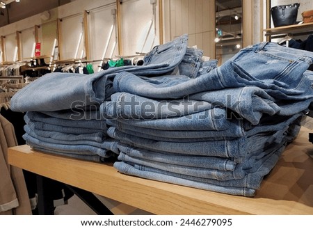 Stack of blue jeans in the store for sale. Jeans trousers stack in a clothing store in the shopping mall. Concept of buy, sell, shopping and jeans fashion. Textile industry. Retail trade
