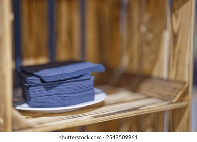 a stack of blue napkins lie on a white plate in a wooden box with flamed wooden strips - Powered by Shutterstock