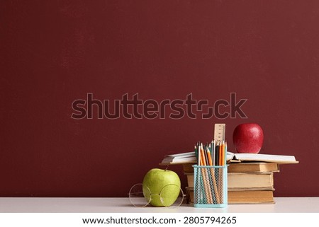 Stack of books with apples and school supplies on desk