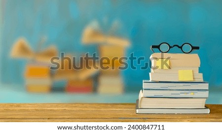 stack of books, bookmarks and spectacles, blurred open books in the background.Spring Book fair , inspiration,reading, education, literature concept, free copy space