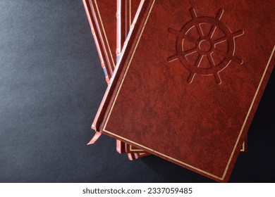 Stack of books with brown leather cover with engraved symbol of buddhist culture and religion on black table. Top view.