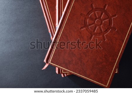 Stack of books with brown leather cover with engraved symbol of buddhist culture and religion on black table. Top view.