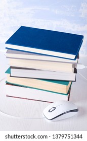 Stack of books and computer mouse on the white table.Concept of online education and free reading
