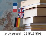 Stack of books with country flags on background of map, foreign language learning concept