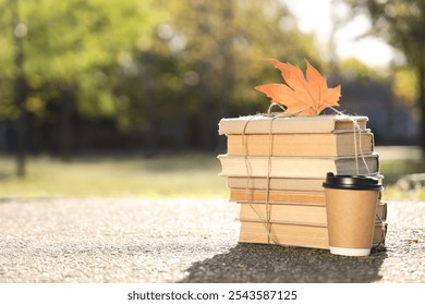 Stack of books, cup of coffee and autumn leaf on road in park - Powered by Shutterstock