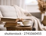 Stack of books and cup of coffee on table in living room, closeup