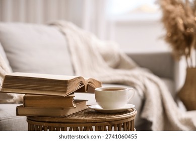 Stack of books and cup of coffee on table in living room, closeup