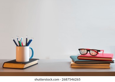 a stack of books and a cup with pencils