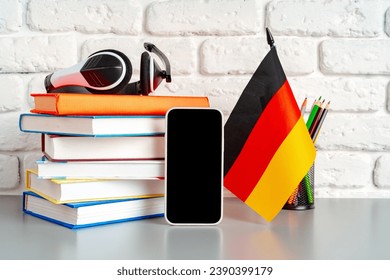Stack of books and flag of Germany on desk. German language learning concept