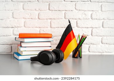 Stack of books and flag of Germany on desk. German language learning concept