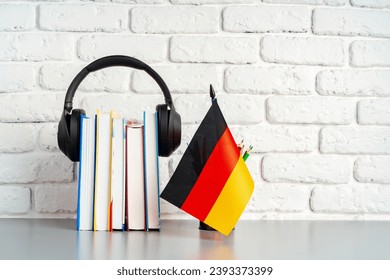 Stack of books and flag of Germany on desk. German language learning concept