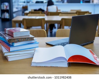Stack of books, laptop computer on table in the library / Education & Back to school concept