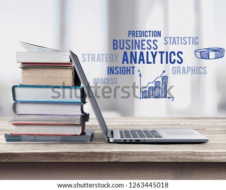 Stack of books with laptop on table