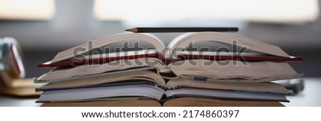 Stack of books lay on table, undone homework tasks or things to learn at home