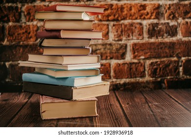 Stack Of Books In The Library Room Lay On The Wood Table With Brick Backround.