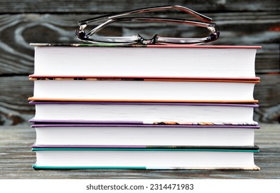 A stack of books lies on the table and glasses on a dark background. Education concept - Powered by Shutterstock