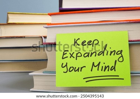 Stack of books and a note with the phrase Keep expanding your mind. Continuous learning and personal growth.