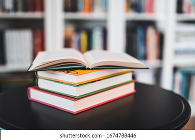 A stack of books on a black table. Library in the background. Stack of books close up.