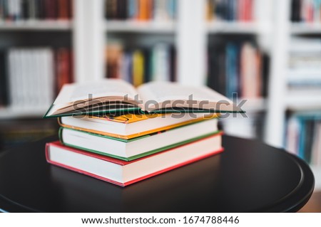 A stack of books on a black table. Library in the background. Stack of books close up.