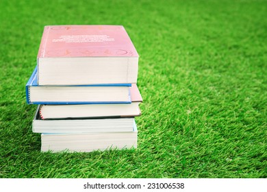 Stack of books on green grass