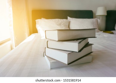 Stack of books on the white bed.  Vintage and grainy effect.