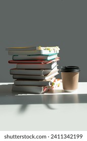 a stack of books on a white table with a coffee glass and a beautiful shadow from the window.