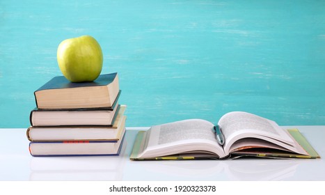 A stack of books, an open book, a green apple on the table.Copy space. - Powered by Shutterstock