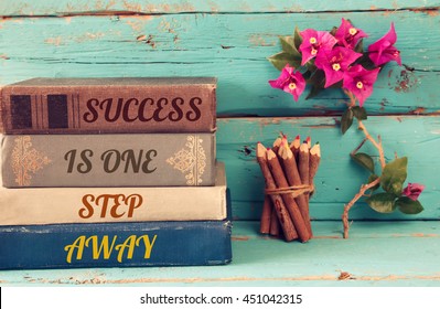 Stack Of Books Over Wooden Table And Motivational Phrase - Success Is One Step Away. 