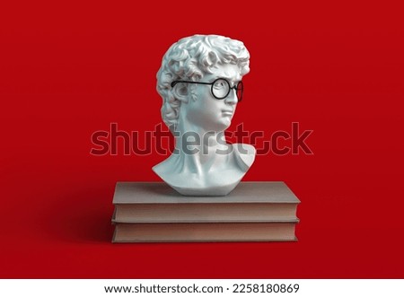 stack of books and sculpture of David's head with eyeglasses on red background. Student and education concept