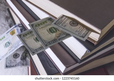 a stack of books, in them dollars, bookmark