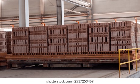 A stack of bricks is piled on top of a pallet. The bricks are brown and appear to be in a warehouse