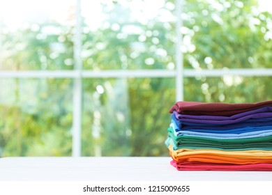 Stack bright folded clothes table against blurred background  Space for text